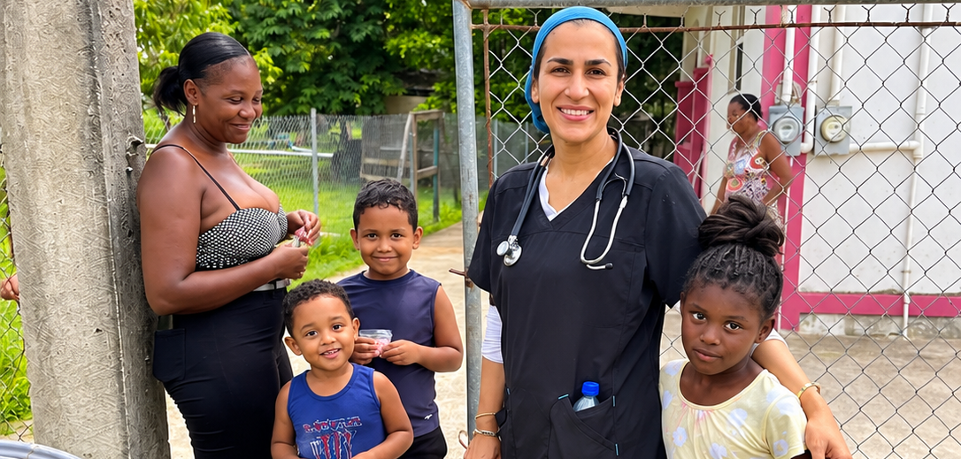 Hope for Humanity doctor in scrubs smiling with community family by gate