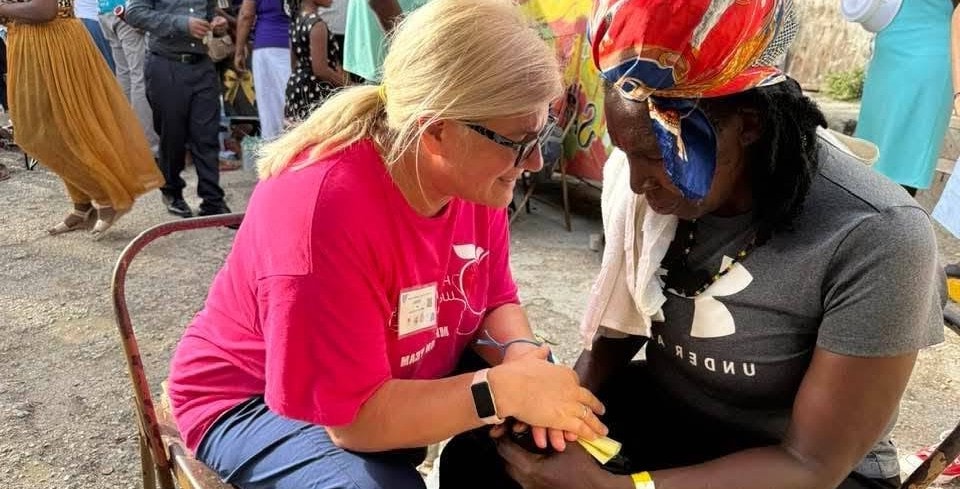Hope for Humanity volunteer in pink shirt providing care at outdoor community event