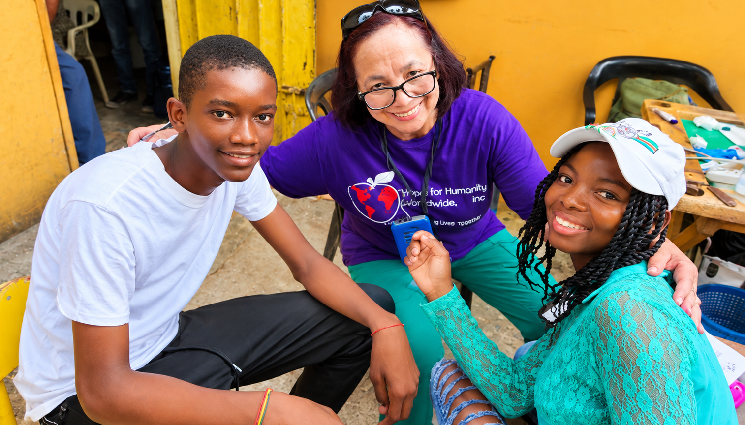 Hope for Humanity volunteer with two teenagers smiling at community event