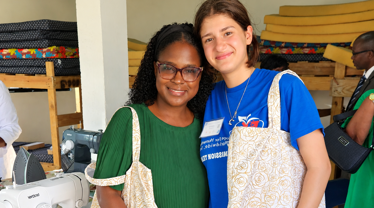 Two Hope for Humanity volunteers smiling together at sewing workshop wearing aprons