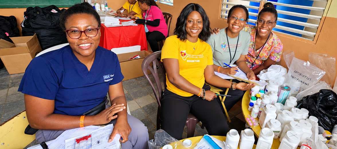 Hope for Humanity mission team volunteers smiling at medical supply station with antibiotics and medications