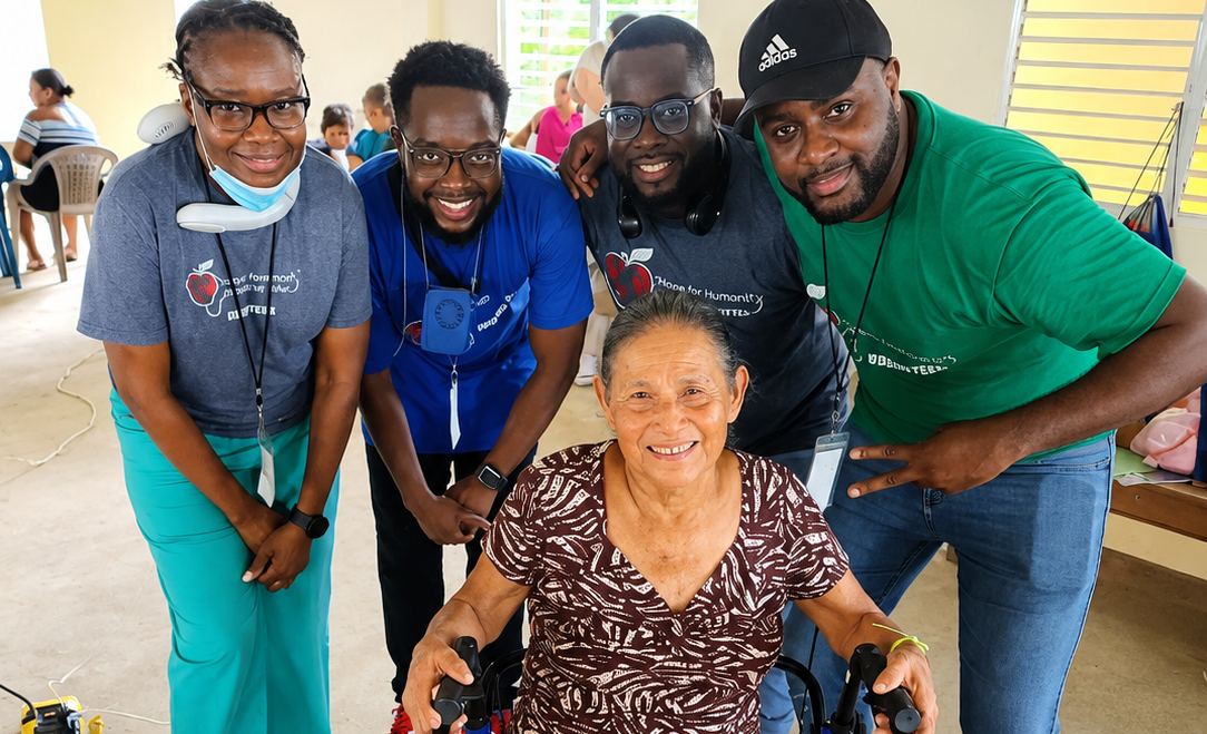 Hope for Humanity mission team members posing joyfully with elderly patient in walker