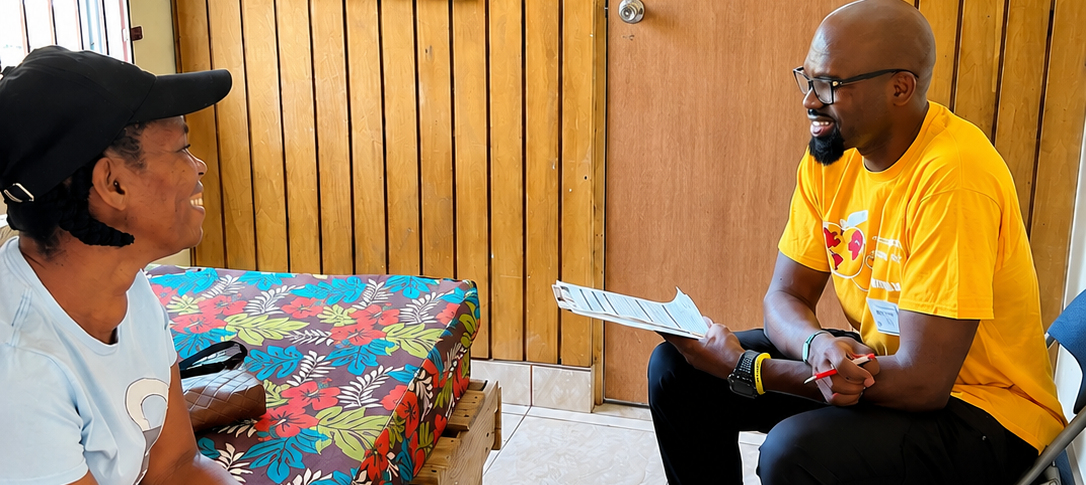 Hope for Humanity volunteer in yellow HHW shirt consulting with community member