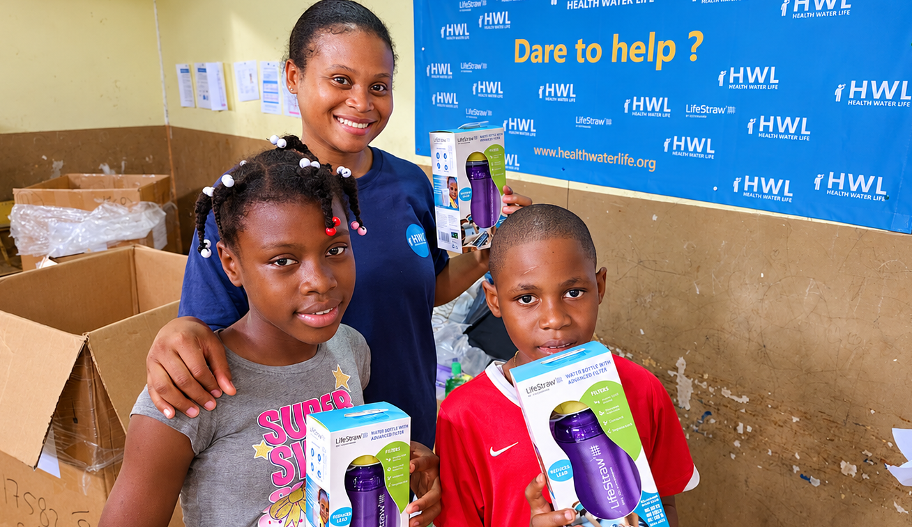 Volunteer distributing LifeStraw water filters to children at Health Water Life community event